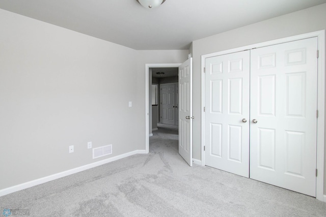 unfurnished bedroom featuring a closet and light carpet