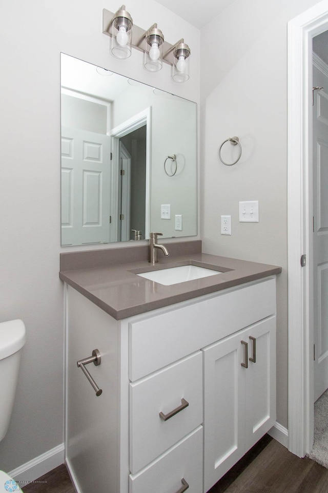 bathroom with vanity, toilet, and hardwood / wood-style floors