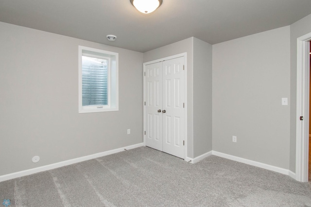 unfurnished bedroom with a closet and light colored carpet