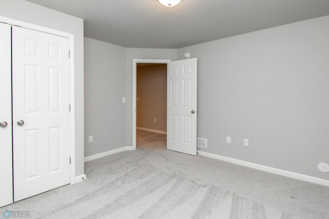 unfurnished bedroom with a closet and light carpet