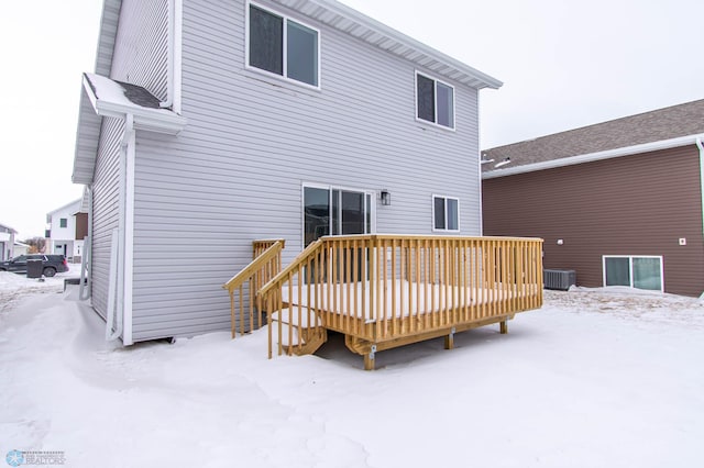 snow covered house with central AC unit and a wooden deck