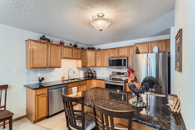 kitchen with stainless steel appliances, decorative backsplash, dark stone countertops, a textured ceiling, and sink