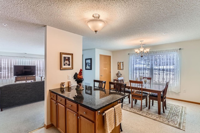 kitchen featuring light colored carpet, pendant lighting, a chandelier, and dark stone countertops