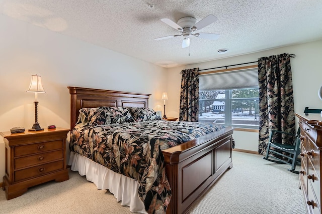 bedroom with ceiling fan, light colored carpet, and a textured ceiling