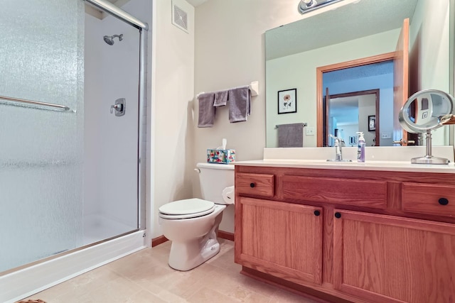 bathroom with a shower with shower door, toilet, vanity, and tile patterned flooring