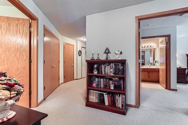 hall with light colored carpet and a textured ceiling