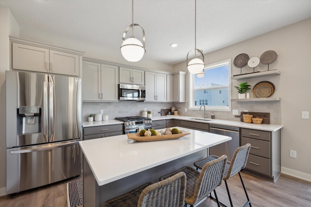 kitchen with sink, gray cabinets, stainless steel appliances, and pendant lighting