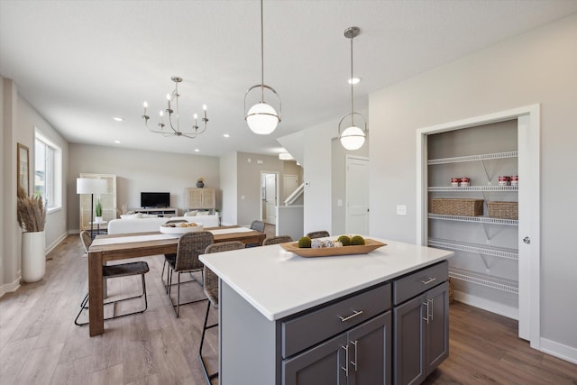 kitchen with a center island, gray cabinetry, hanging light fixtures, a chandelier, and light hardwood / wood-style flooring