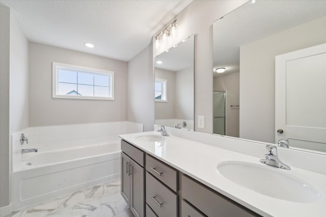 bathroom featuring a textured ceiling, a bathtub, and vanity