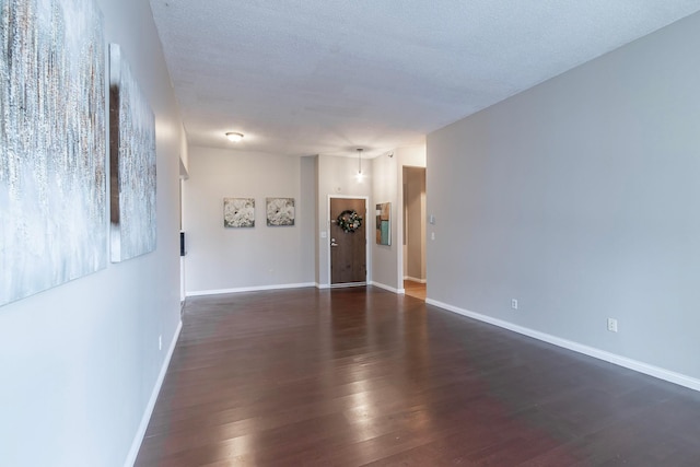 spare room with a textured ceiling and dark hardwood / wood-style flooring