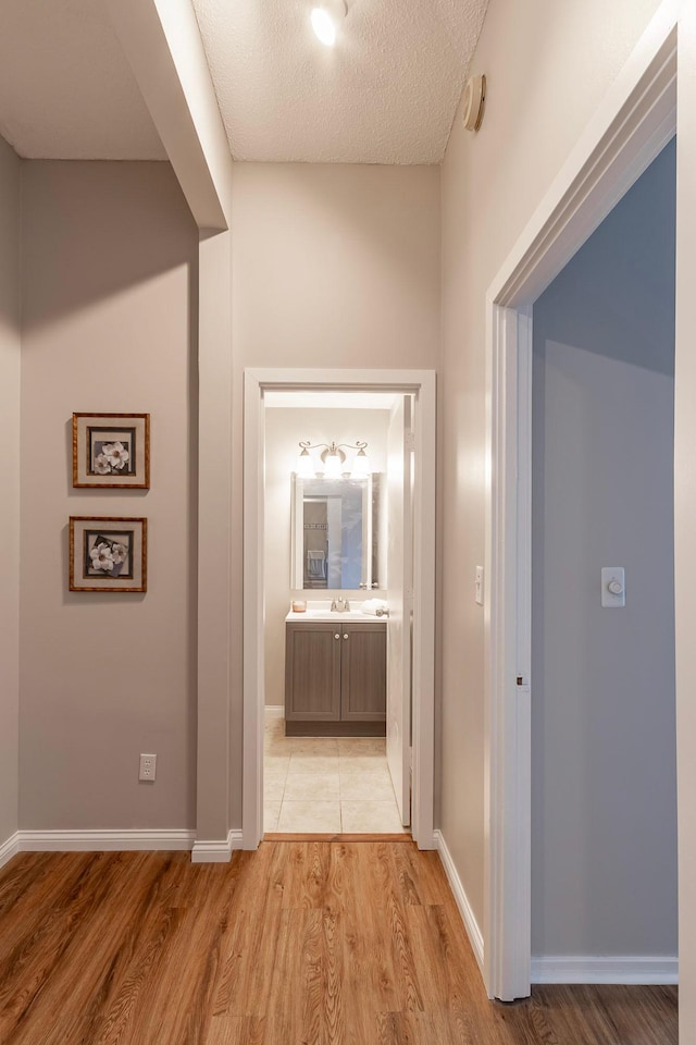 hall with a textured ceiling and light hardwood / wood-style floors