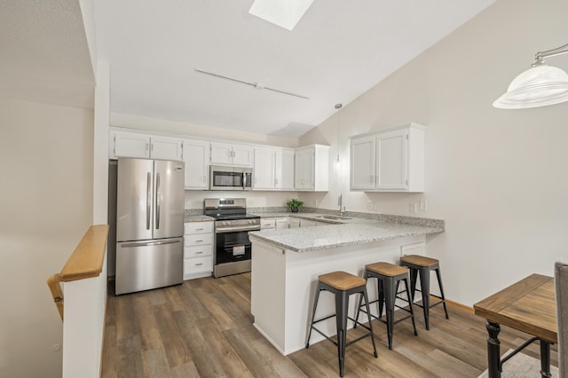 kitchen featuring kitchen peninsula, sink, hanging light fixtures, appliances with stainless steel finishes, and white cabinets