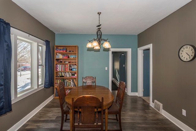 dining area featuring baseboards, visible vents, a chandelier, and dark wood-style flooring