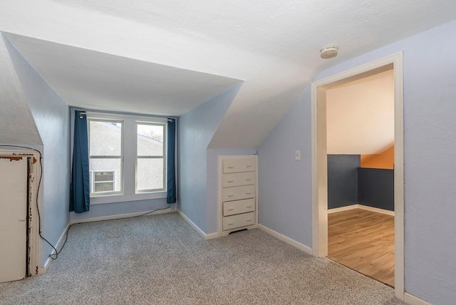 additional living space with carpet, baseboards, and vaulted ceiling