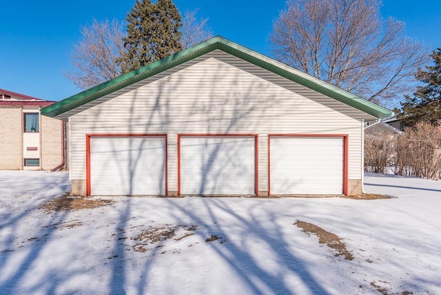 snow covered garage featuring a detached garage