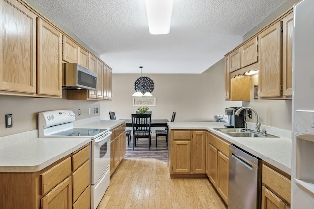 kitchen featuring sink, decorative light fixtures, light hardwood / wood-style flooring, a textured ceiling, and appliances with stainless steel finishes