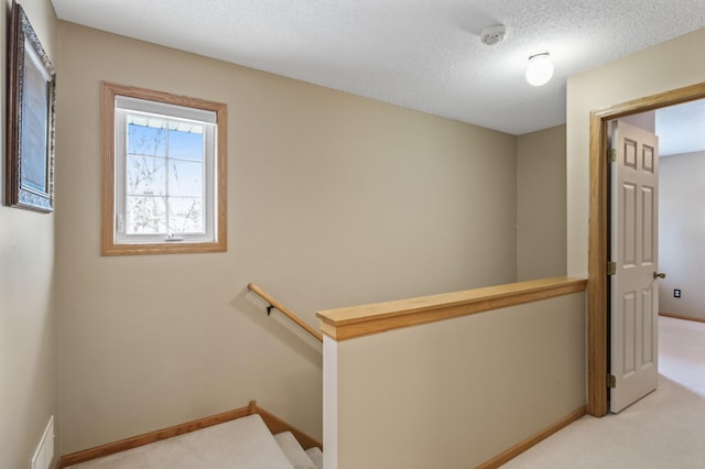 corridor featuring light colored carpet and a textured ceiling