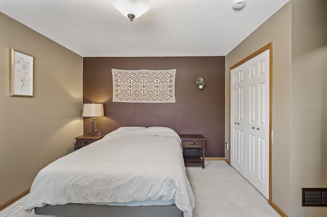 bedroom with light colored carpet, a closet, and a textured ceiling