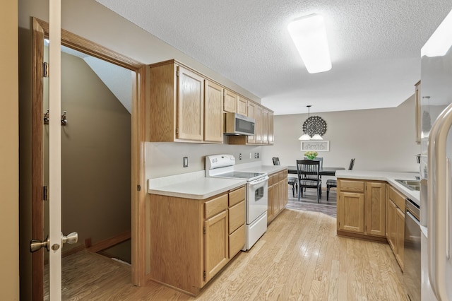 kitchen featuring hanging light fixtures, appliances with stainless steel finishes, light brown cabinets, and light wood-type flooring