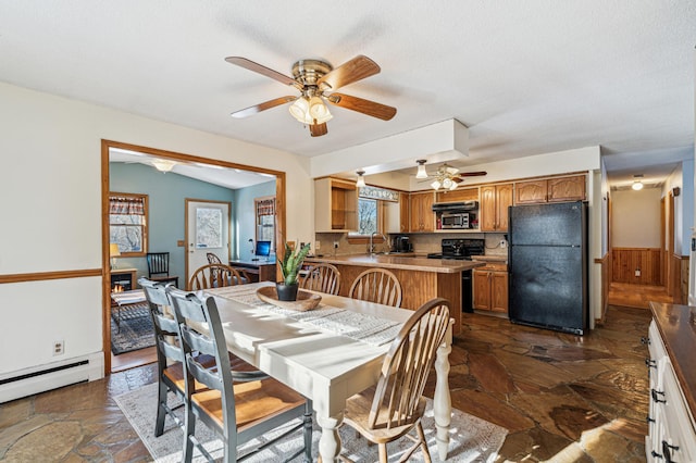 dining space featuring lofted ceiling, sink, a textured ceiling, baseboard heating, and ceiling fan