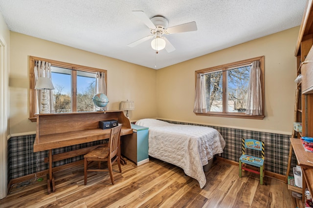 bedroom with a textured ceiling, light hardwood / wood-style flooring, and ceiling fan