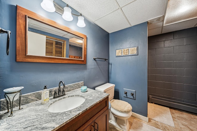 bathroom with baseboard heating, a paneled ceiling, vanity, and toilet