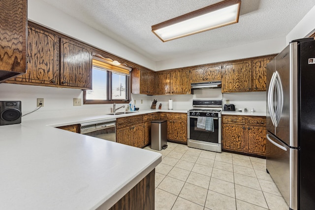 kitchen featuring dishwashing machine, a textured ceiling, sink, stainless steel fridge, and gas range oven