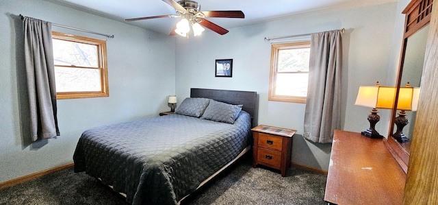 bedroom featuring multiple windows, dark carpet, and ceiling fan