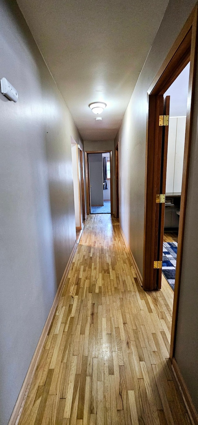 hallway with light wood-style flooring and baseboards