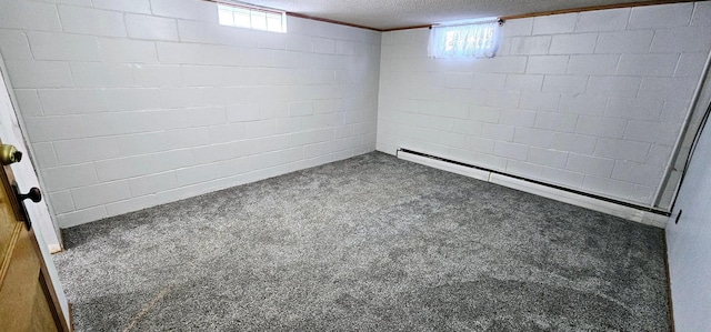 basement featuring baseboard heating, a healthy amount of sunlight, a textured ceiling, and dark colored carpet