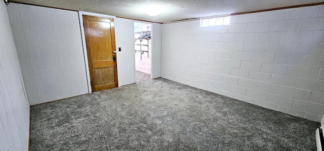 interior space with a textured ceiling, carpet, and concrete block wall