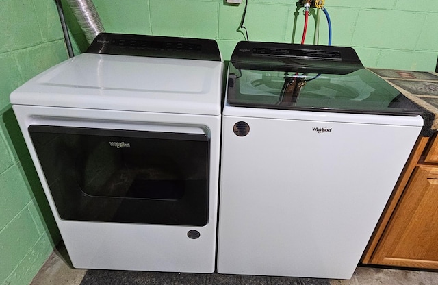 washroom with concrete block wall, laundry area, and washer and clothes dryer