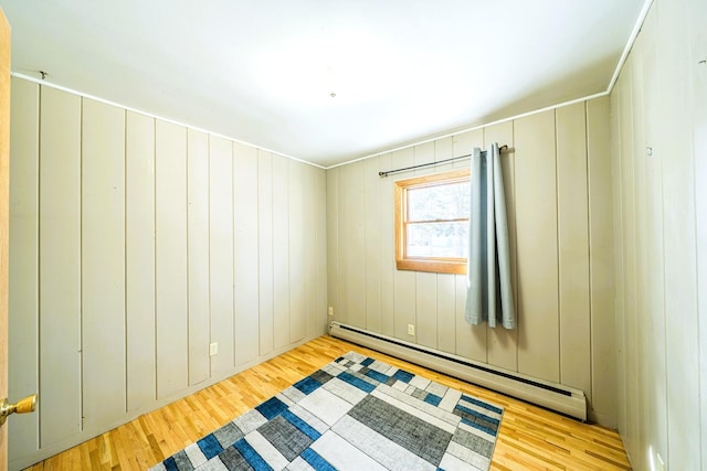 unfurnished room featuring a baseboard heating unit and wood finished floors