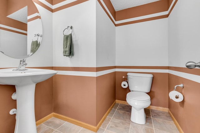 bathroom with baseboards, a sink, and toilet