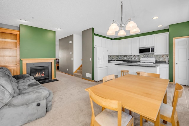 kitchen featuring white appliances, white cabinets, decorative backsplash, a fireplace with flush hearth, and a center island