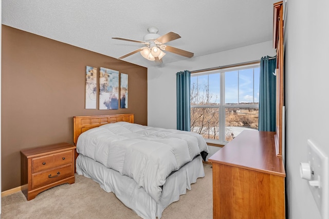 bedroom featuring light carpet, ceiling fan, and a textured ceiling