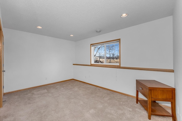 empty room featuring light carpet, baseboards, a textured ceiling, and recessed lighting