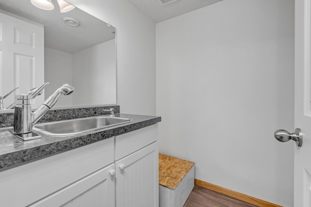 bathroom featuring vanity, baseboards, a textured ceiling, and wood finished floors