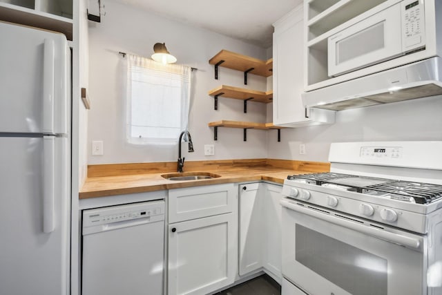 kitchen with sink, custom exhaust hood, white cabinetry, wooden counters, and white appliances