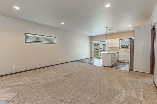 kitchen featuring pendant lighting, white cabinets, a kitchen island, stainless steel fridge, and carpet flooring