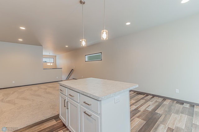 kitchen with decorative light fixtures, light hardwood / wood-style floors, white cabinetry, and a kitchen island