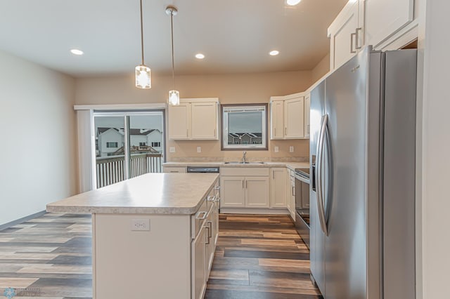 kitchen featuring a center island, white cabinetry, hanging light fixtures, appliances with stainless steel finishes, and dark wood-type flooring