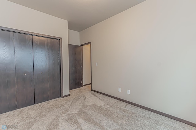 unfurnished bedroom with a closet and light colored carpet