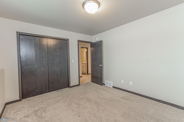 unfurnished bedroom with a closet and light carpet