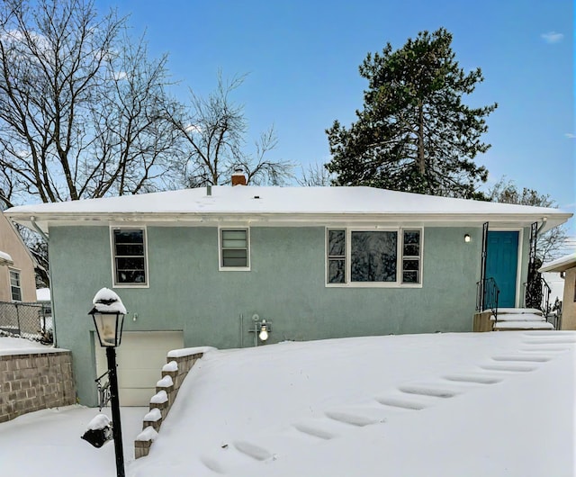 snow covered house featuring a garage