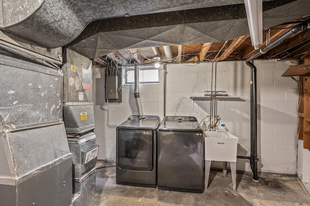 washroom featuring electric panel, heating unit, washer and clothes dryer, and sink