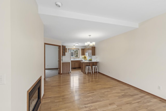 unfurnished living room with a chandelier and light wood-type flooring