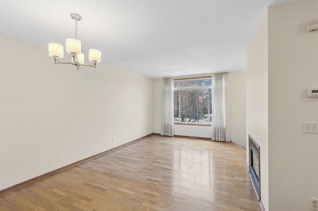 unfurnished room featuring light wood-type flooring and a chandelier