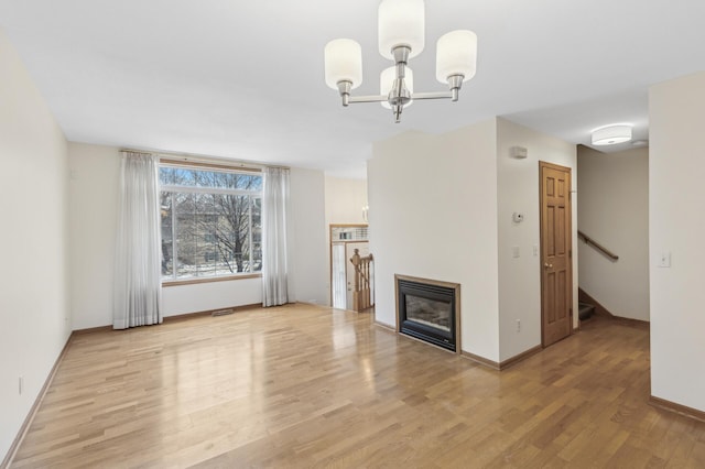 unfurnished living room with an inviting chandelier and light hardwood / wood-style flooring