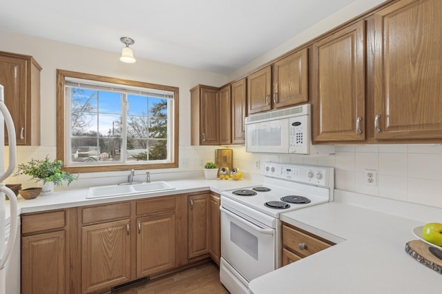 kitchen with backsplash, white appliances, sink, and light wood-type flooring